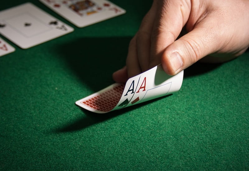 Ein Dealer deckt zwei Asse beim Poker auf.