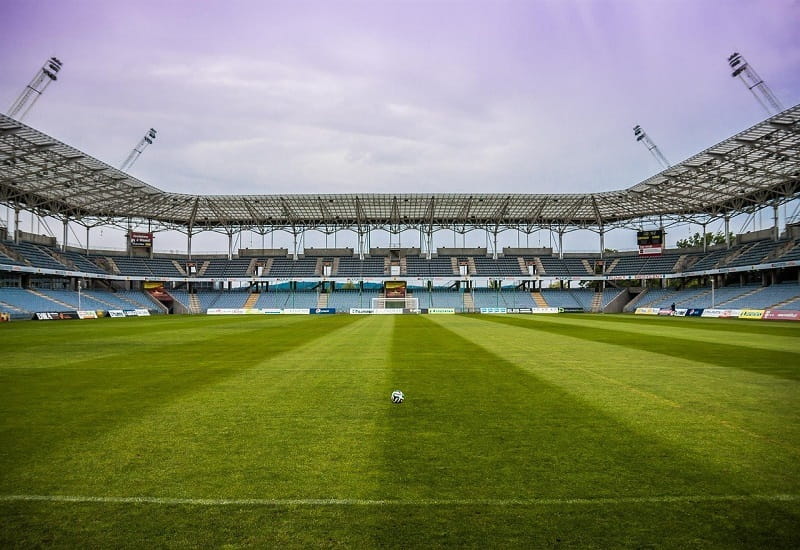 Ein Fußball liegt auf dem Rasen eines leeren Stadions.