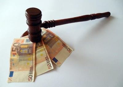 Ein Gerichtshammer steht auf drei 50-Euro-Scheinen.