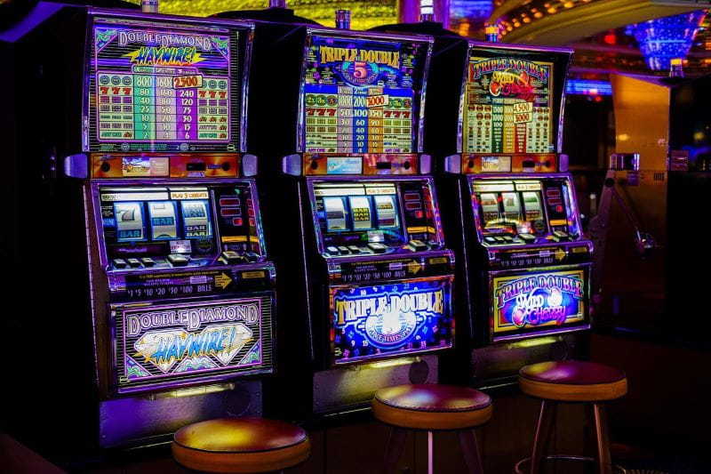 Drei aktive Glücksspielautomaten stehen nebeneinander.