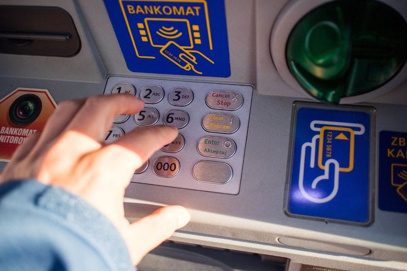 Eine Person tippt am Geldautomaten die Geheimzahl ein.