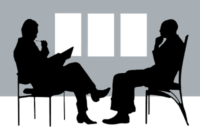 Zwei gezeichnete Männer sitzen sich gegenüber und führen ein Gespräch.