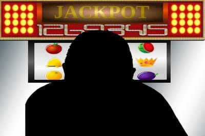 Animation: Eine männliche Person sitzt vor einem Jackpot-Spielautomaten.
